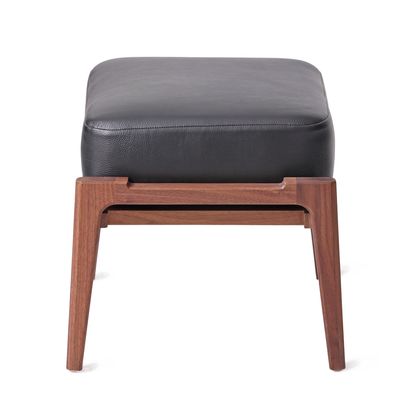 Modern ottoman with natural walnut wooden frame and black leather cushion, ideal for complementing lounge chairs in contemporary home or office decor.